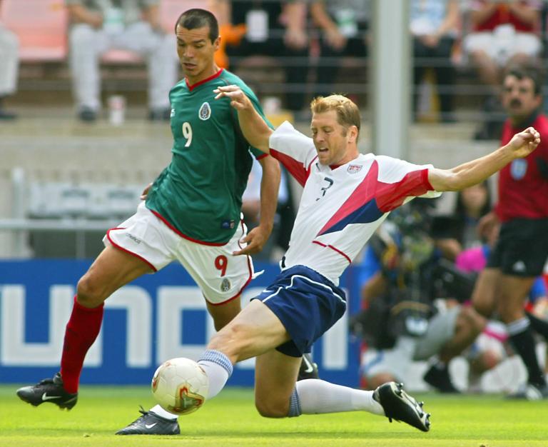 JEONJU, REPUBLIC OF KOREA: USA's Gregg Berhalter (R) beats Mexico's Jared Borgetti (L) to the ball, 17 June 2002 at the Jeonju World Cup Stadium in Jeonju, during second round playoff action between Mexico and USA in the 2002 FIFA World Cup Korea/Japan. AFP PHOTO/ROBYN BECK (Photo credit should read ROBYN BECK/AFP via Getty Images)